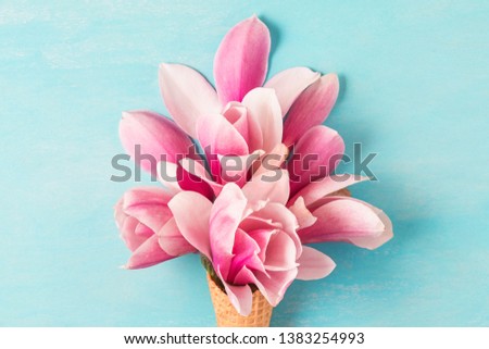 pink magnolia flowers bouquet in ice cream cone on blue background. wedding or holiday background. Flat lay. top view. close up