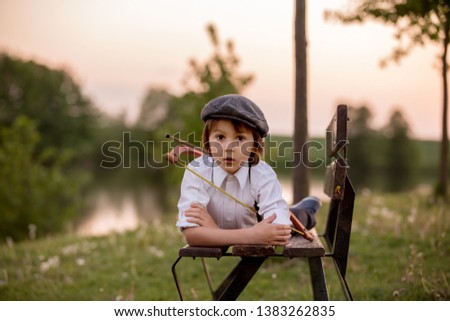 Portrait of child playing with bow and arrows, archery shoots a bow at the target on sunset Royalty-Free Stock Photo #1383262835