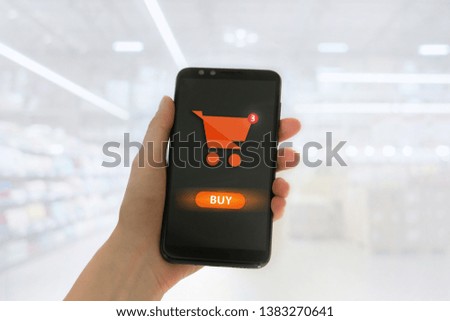 Hand holding mobile smart phone with my shopping carts screen on Supermarket blur background