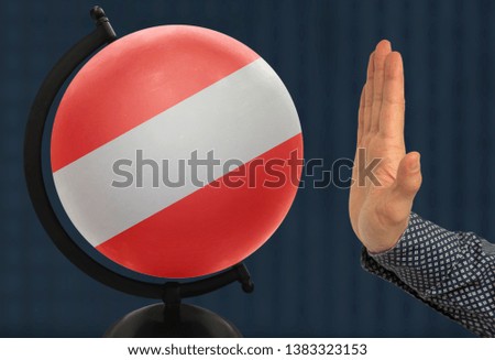 gesture of a male hand warns against the globe, which depicts a colored national state flag Austria