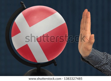 The warning gesture of a man’s hand refers to a globe with a colored national state flag denmark
