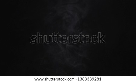 Close-up of white puffs of cigarette smoke in the dark on the black background. Action. Smoke in darkness