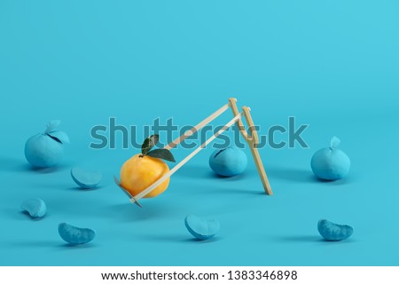 Outstanding mandarin orange in a slingshot surrounded by oranges painted in blue on blue background. Minimal fruit idea concept.