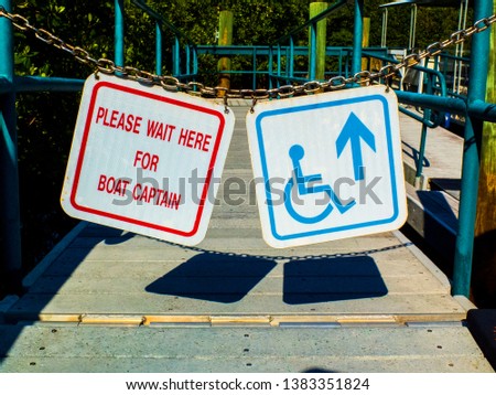 Pantoon boat entrance with a sign that reads Please Wait Here For Boat Captain and a Blue Handicap Accessible sign.