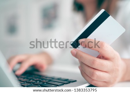 Hands holding plastic credit card and using laptop. Online shopping concept. Toned picture 