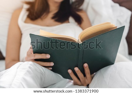 Young asia woman reading book on bed at her hoom, Selective focus.