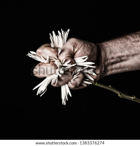 Artistic picture of flowers symbolically being crushed with fist