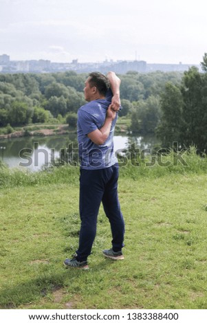 Korean man stretches against the background of the city. Healthy lifestyle. Adult man  practicing yoga in nature.