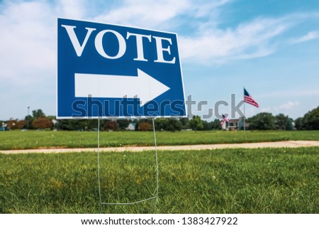 Vote sign with arrow  against the sky with American flags in the background