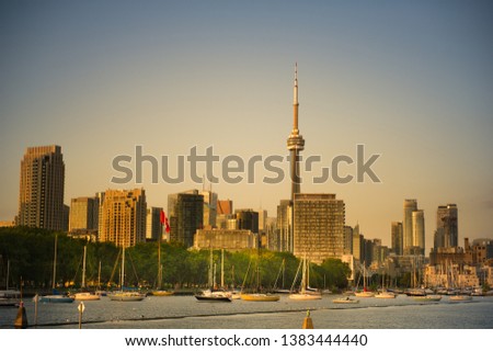 Panorama of Toronto skyline at sunset in Ontario, Canada. Boats are visible in foreground. The CN Tower is standing out between the downtown skyscrapers.