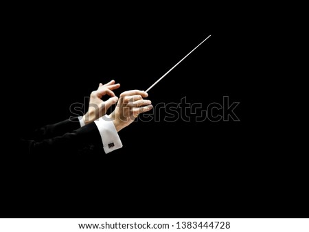 Hands of conductor on a black background  Royalty-Free Stock Photo #1383444728