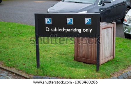 Disabled and handicapped parking signboard for cars and other vehicles and also green grass on the ground.