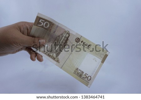 Hand holding MOP Macao bank notes