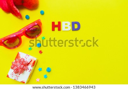 Happy birthday greeting card with gift box,glasses,beads on yellow background with copy space