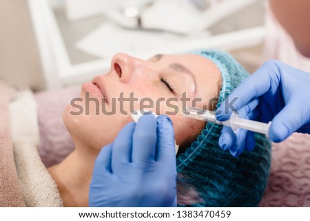 Closeup of cosmetologist hands making facial lifting injection for woman