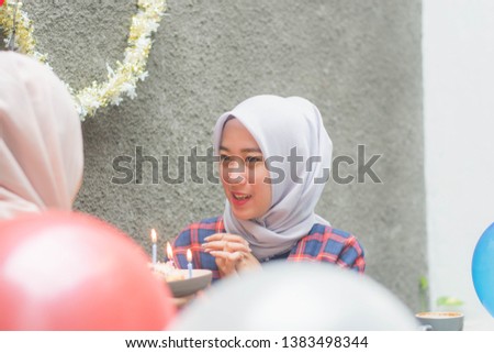 attractive hijab woman having surprise birthday cake from her bestfriend with candle while sitting on cafe -image