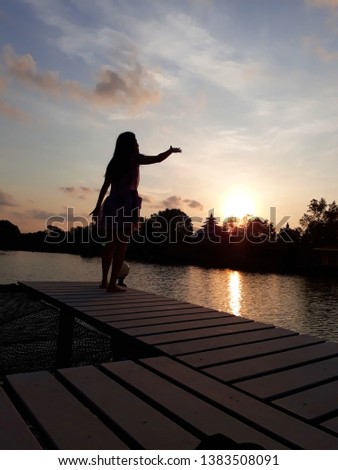 Silhouette  girl  on wooden bridge  with  beautiful  landscape view under  morning sunlight  use for   park and outdoor background or wallpaper .
