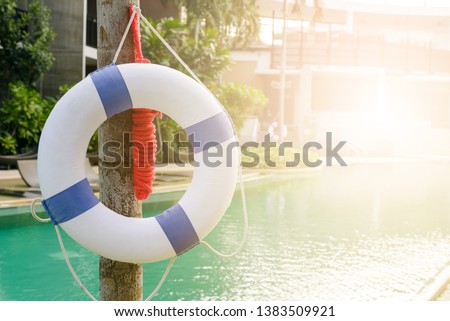 white and blue life buoy hanging near swimming pool