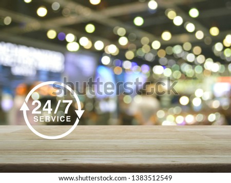 24/7 service icon on wooden table over blur light and shadow of shopping mall, Full time service concept