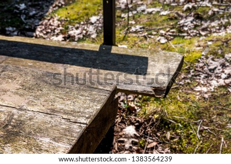 Abstract cut image of a weathered solid wood table and a deliberately blurred wooden bench behind the table, abstract