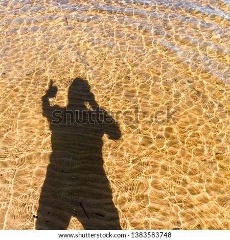 happy man shadow on the water on the beach - summer vacation concept