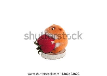 The handmade toy made of felt is a hamster biting strawberry on a white isolated background.