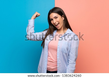 Young woman over pink and blue wall proud and self-satisfied