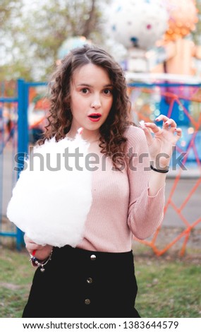 Close up portrait of a happy smiling excited girl holding cotton candy at amusement park