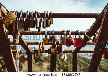 padlocks on rusty bar with blurred view of Barcelona from Tibidabo mountain on sunny summer day, Barcelona, Catalonia, Spain