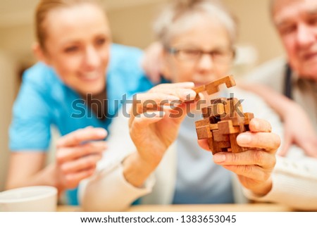 Demented senior woman puts blocks of wood together in the nursing home as a patience game Royalty-Free Stock Photo #1383653045