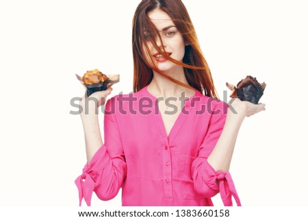 Red-haired woman in a pink shirt holding cupcakes in her hands                       
