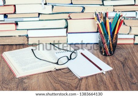 Stack of books, hardback books on wooden table, open book, notebook and glasses, copy space for text