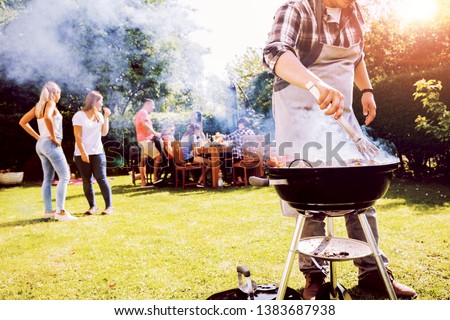 Summer garden bbq party with grill and people in background Royalty-Free Stock Photo #1383687938