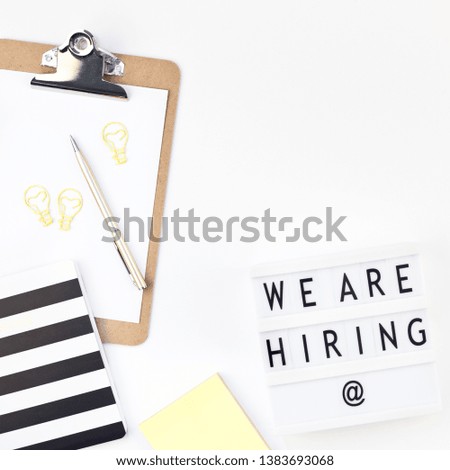 Creative top view flat lay of desk with we are hiring text on lightbox with copy space on white background in minimal style. Concept of new job, hiring recruitment process, new team members screening