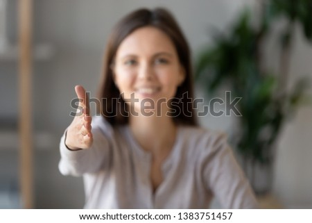 Focus close up of smiling young female employer stretch hand greeting potential job candidate at hiring meeting, happy woman boss shake hand introducing welcome applicant at interview in office