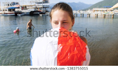 Closeup portrait of mother inflating beach ball for her child on the beach