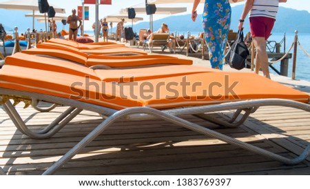 Closeup image of sunbeds with towels and matrasses on wooden pier at sea shore. Concept of summer holidays on beach