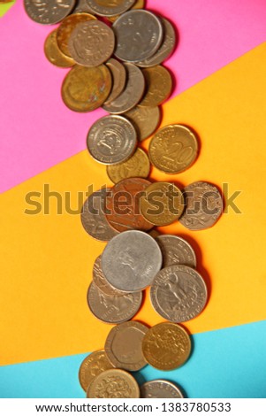 Different countries coin and pennies stack on colorful paper. This photo showing economical success in different range and variety. 