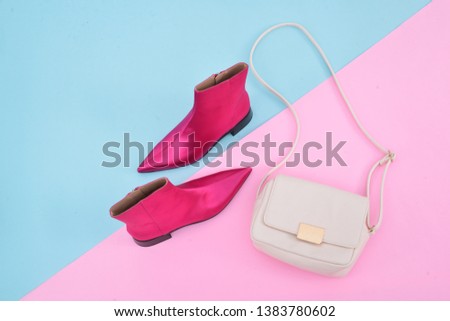 White leather handbag with red boots shoes isolated blue and pink background
