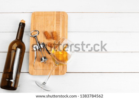 Bottle of wine and cork and corkscrew on wooden table