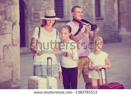 Young parents with kids  taking photo and holding map during their vacation