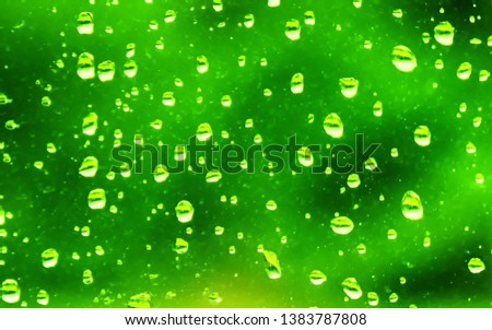 Background texture of window glass covered with water drops after spring rain shower. Blurred spring greenery in the background.  
