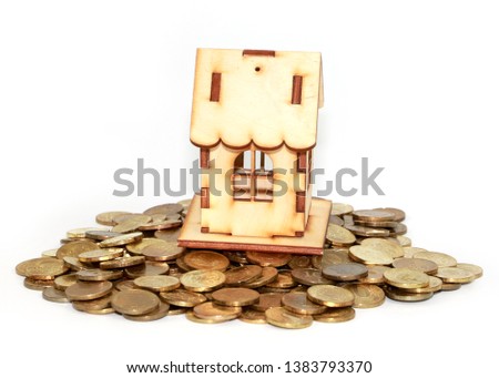 wooden house on a pile of gold coins as a symbol of mortgage lending