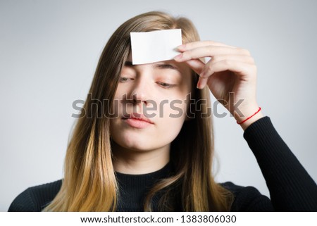 portrait of beautiful girl holding sticker in forehead, studio photo over gray background