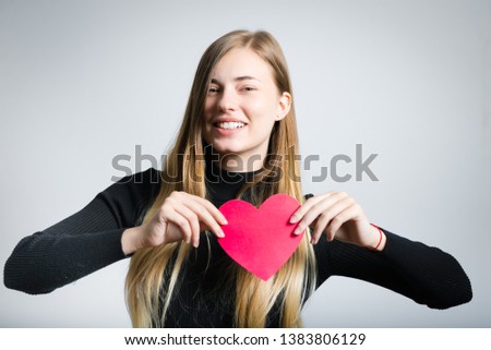 beautiful girl with paper heart in hands, studio photo over background