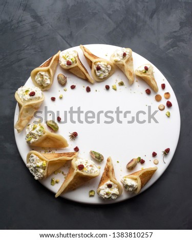 Qatayef is an Arabic dessert usually served during the month of Ramadan, pancakes filled with cream or cottage cheese and pistachios. Royalty-Free Stock Photo #1383810257