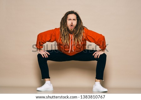 A man in a red sweater and black trousers sneakers open mouth dreadlocks on his head           