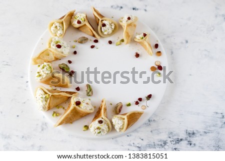 Qatayef - Arabic dessert, which is usually served during the month of Ramadan, pancakes filled with cream or cottage cheese and pistachios, decorated with dried strawberries. Royalty-Free Stock Photo #1383815051