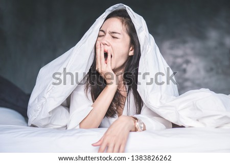 sleepless Asian woman wake up on bed and yawning feeling tired  Royalty-Free Stock Photo #1383826262