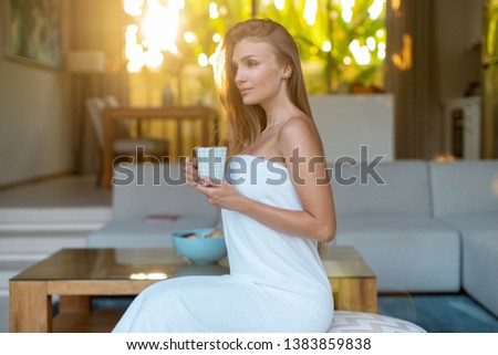 
Beautiful girl in the morning after a shower in a towel drinks coffee